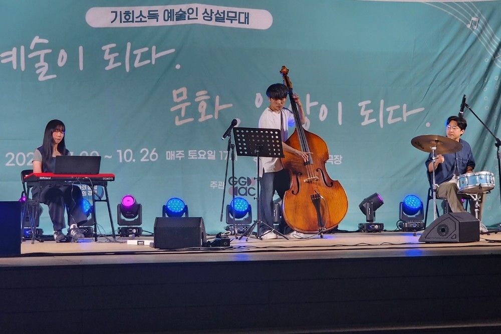 조명이 켜진 무대에서 드럼을 포함한 편성으로 공연하는 모습