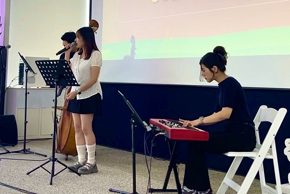 실내 무대에서 보컬, 피아노, 콘트라베이스로 공연하는 모습